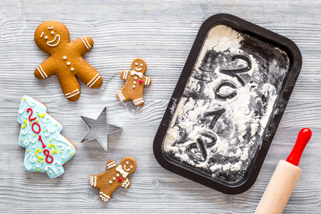 Make gingerbread cookie for new year 2018. Gingerbread man, rolling pin, flour on grey wooden background top view.の写真素材