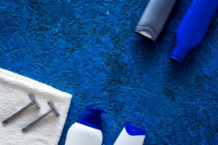 Men's cosmetics for hair care and shaving. Shampoo, gel, razor, wax on blue background top view.の写真素材