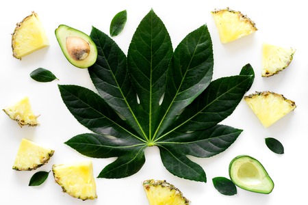 Pinneapple slices and leaves pattern on white background top view.