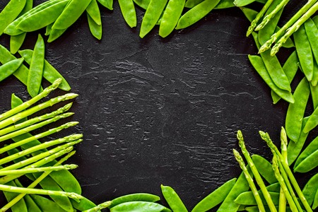 Green pea pods and asparagus on black background top view copyspaceの写真素材