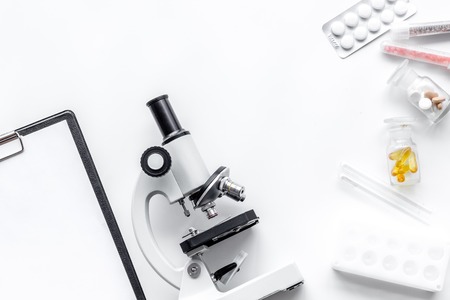 Doctor's workplace. Microscope, pills and test tube on white background top view.の写真素材