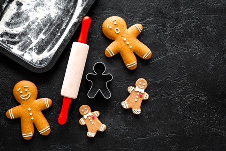 Cook gingerbread for new year 2018. Gingerbread man, rolling pin, flour on black background top...