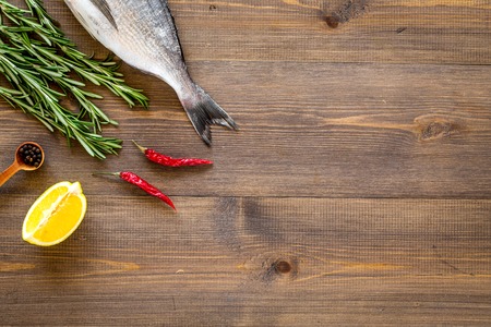 Cooking sea fish with spices rosemary, pepper, chili, lemon. Wooden background top view.の写真素材