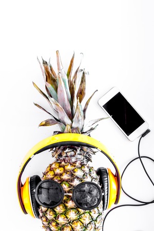 Cool pineapple in sunglasses is music lover. White background top view.の写真素材