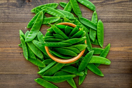 Fresh pea pods in bowls on dark wooden background top view.の写真素材