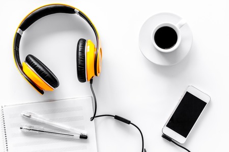 Worktable of composer today. Headphones, phone, music notes on white background top view.の写真素材