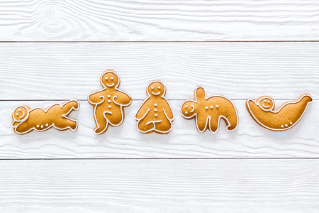 Gingerbread cookies in shape of yoga asanas on white wooden background top view.の写真素材