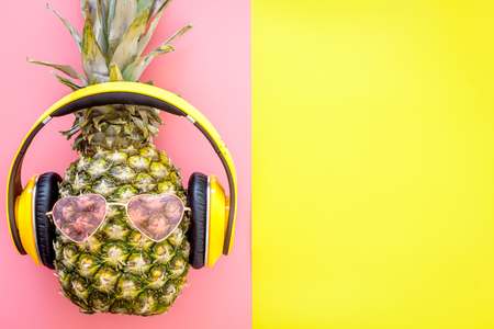 Pineapple in sunglasses and headphones on pink background top view.の写真素材