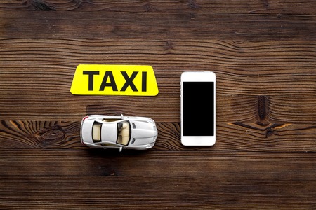 Online order a taxi set with car toy and mobile phone on wooden desk background top view mock upの写真素材