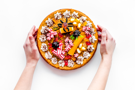 Hand take pumpkin pie for halloween decorated gummy spiders. White background top view.の写真素材