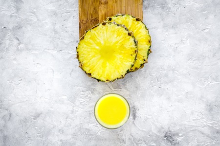 Non-alcoholic beverages. Bottle with fruit juice near pineapples slices on grey background top view copyspaceの写真素材