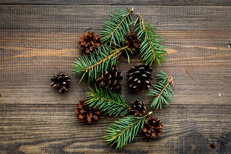 Spruce branch and pinecone pattern on wooden background top view.