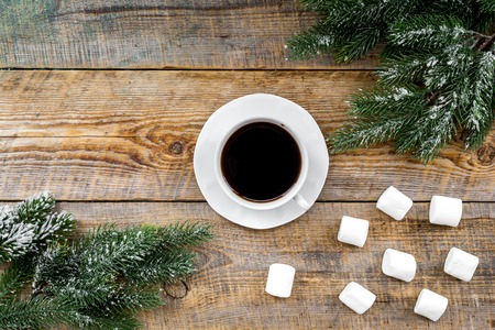Christmas evening. Cup of coffee near spruce branch on rustic wooden background top view.の写真素材