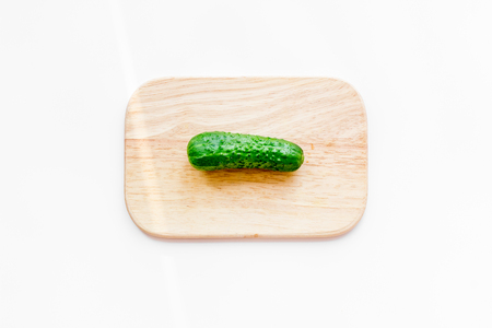 Make salad with fresh cucumbers. Vegetables on cutting board on white background top view.の写真素材