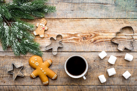 Christmas evening. Gingerbread man, coffee and spruce branch on wooden background top view.