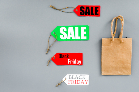 Sale and black friday labels near paper shopping bag on grey background top view.の写真素材