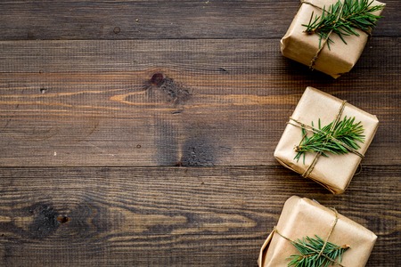 Gifts for new year wrapped in craft paper near spruce branches and cones on wooden background top view.の写真素材