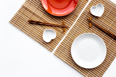 Table setting for sushi roll. Empty plate on mat near chopstick and bowl for sause on white background top view copyspaceの写真素材