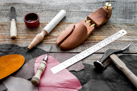 Clobbers desk. Tools, wooden last, pieces of leather on wooden background