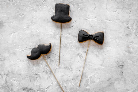 Men birthday concept. Set of cookies in shape of black tie, mustache and hat. Grey stone background...