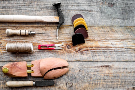 Shoe repair. Wooden last, hammer, awl, knife, thread on wooden background top view copyspace