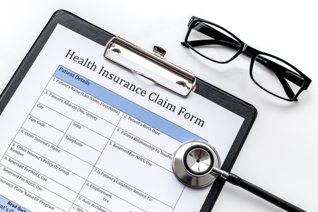 Health insurance for reception at the doctor. Document, stethoscope, pad, glasses on white background top viewの写真素材