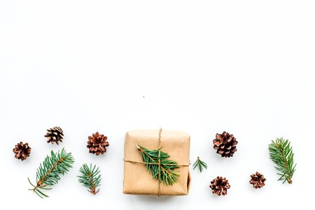 Gifts for new year wrapped in craft paper near spruce branches and cones on white top view copyspaceの写真素材