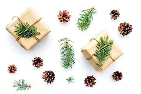 Gifts for new year wrapped in craft paper near spruce branches and cones on white background top view.の写真素材