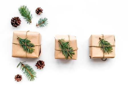 Gifts for new year wrapped in craft paper near spruce branches and cones on white background top view.の写真素材