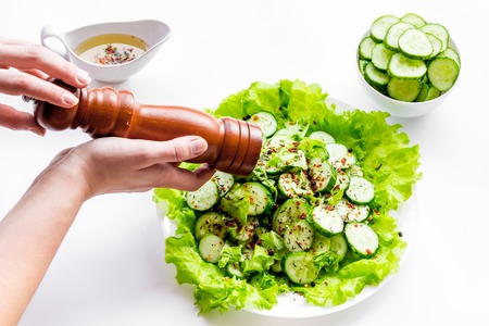 Hands pepper salad with fresh cucumbers and lettuce. White background.の写真素材