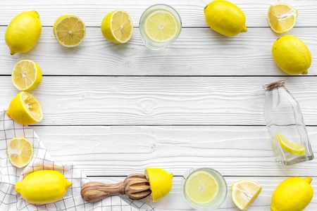 Make lemonade at home. Lemons, juicer, glass and bottle for beverage on white wooden background top view.の写真素材