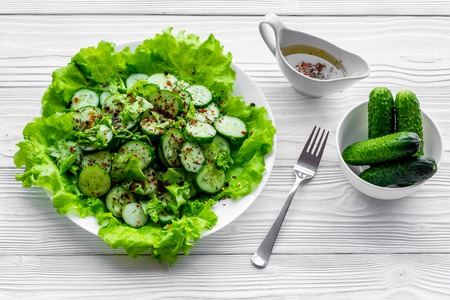 Salad with fresh cucumbers and lettuce near gravy boat. Grey wooden background.の写真素材