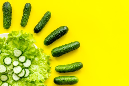 Pattern with fresh cucumbers and salad. Yellow background top view.の写真素材