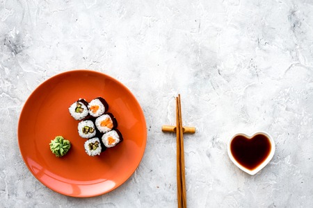 Sushi roll with salmon and avocado on plate with soy sauce, chopstick, wasabi on grey stone background top view.の写真素材