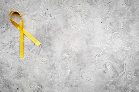 Yellow ribbon for suicide and endometriosis awareness on grey stone background top view.の写真素材