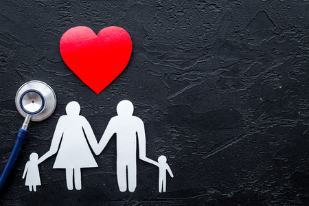 Choose health insurance. Stethoscope, paper heart and silhouette of family on black stone background top view copyspaceの写真素材