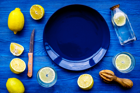 Fresh homemade lemonade. Lemons, juicer, glass for beverage on blue wooden background top view mockupの写真素材