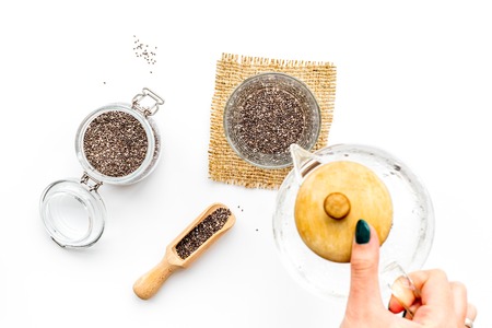 Hand brew chia seeds. Jar with seeds, scoop, bowl, tea pot with hot water. White background top viewの写真素材
