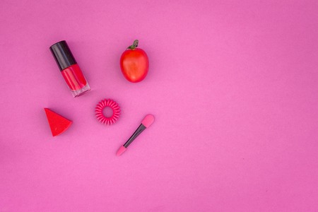 Cosmetics on colorful background. Bright pink nail polish, lipstick, eyeshadow applicator on pink background top view copyspaceの写真素材