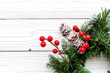 Christmas wreath woven of spruce branches with red berries on white wooden background top view closeup copyspaceの写真素材