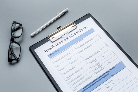 Health insurance for reception at the doctor. Document, pen, glasseson dark grey backgroundの写真素材
