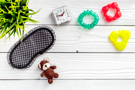 Healthy sleep for children. Sleep mask, plant, alarm clock, toys on white wooden background top view copyspaceの写真素材