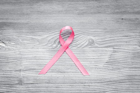 Pink ribbon for breast cancer awareness on grey wooden background top view.の写真素材