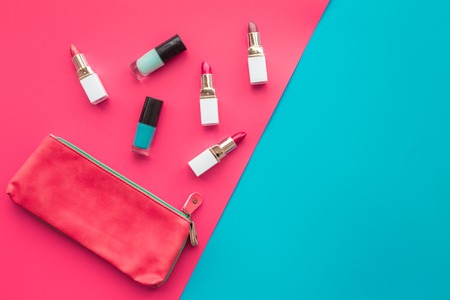 Lipsticks assorted colors and nail polish near cosmetic bag on blue and pink background top view copyspaceの写真素材