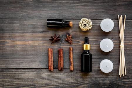 Skin care and relax. Cosmetics and aromatherapy concept. Oil and candles with spices cinnamon on dark wooden background top view copyspaceの写真素材