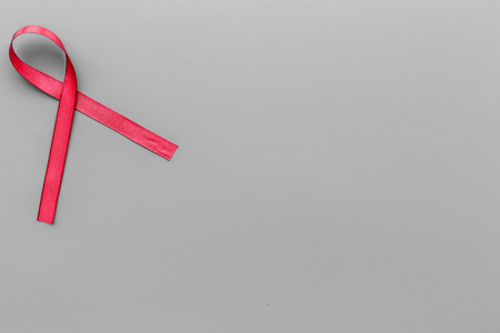 Red ribbon for HIV, AIDS, substance-abuse and anorexia awareness on grey wooden background top view copyspaceの写真素材