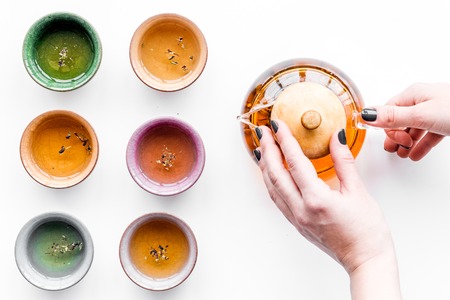 Tea ceremony concept. Hand takes tea pot near cups on white background top view copyspaceの写真素材