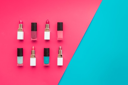 Decorative cosmetics concept. Lipsticks assorted colors and nail polish on red and blue background top view copyspaceの写真素材