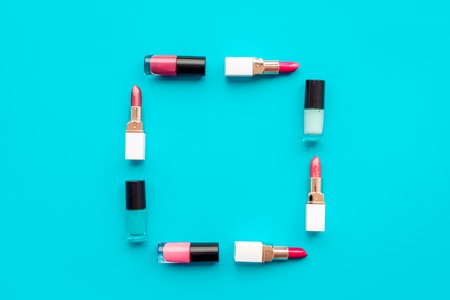 Decorative cosmetics concept. Lipsticks assorted colors and nail polish on blue background top view copyspaceの写真素材