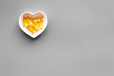 Treat heart. Pills in bowl in shape of heart on grey background top view copyspaceの写真素材